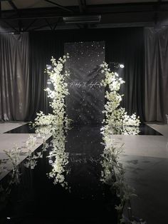 a black and white photo with flowers on the floor in front of a curtained area