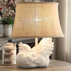 a lamp that is sitting on top of a table next to a chicken figurine