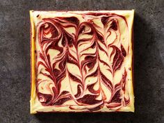 a square piece of cake with red swirls on it