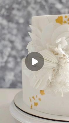 a white and gold wedding cake with flowers on the top is featured in this video