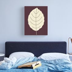 a bed with a blue comforter and an orange leaf mounted on the wall above it