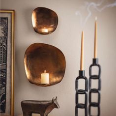 two brass plates on a wall next to candles and other decorative items in front of a framed photograph