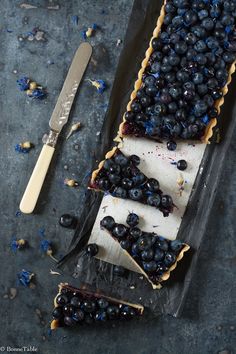 a blueberry tart is cut in half and ready to be eaten with a knife