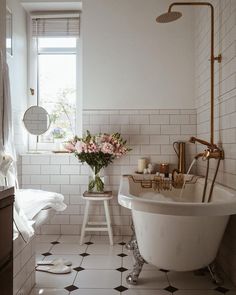 a white bathroom with black and white tile flooring, a claw foot bathtub next to a window