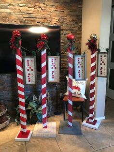 three tall red and white candy canes in front of a fireplace