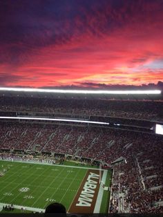 a football stadium filled with lots of people watching the game at sunset or sunrise time