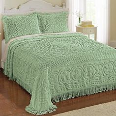 a bed with a green bedspread and pillows