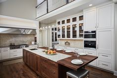 a large kitchen with white cabinets and wooden counter tops, along with an island in the middle