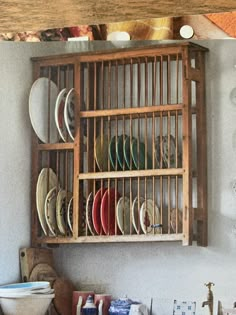 a wooden shelf filled with plates and bowls on top of a counter next to a wall