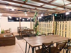 an outdoor dining area with wooden tables and chairs, lights strung from the rafters