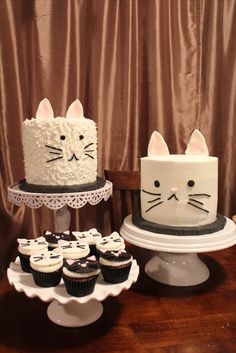 two cakes and cupcakes with cats on them sitting on top of a table