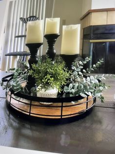 three candles are sitting on top of a tray with greenery in front of a fireplace