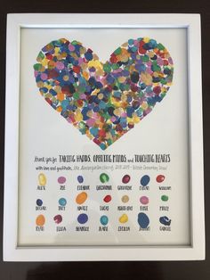 a heart made out of confetti sitting on top of a white framed frame