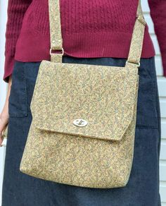 a woman wearing a pink sweater and blue skirt holding a yellow floral handbag in front of her