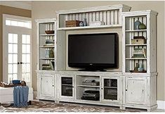 an entertainment center with a large television on it's stand and shelves in front of the tv