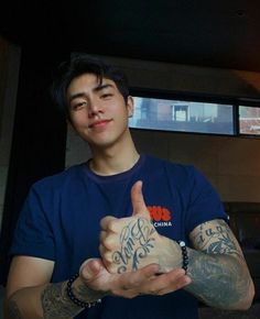 a man with tattoos giving the thumbs up sign while holding his hand in front of him