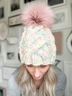 a woman with blonde hair wearing a pink and blue hat while looking at her cell phone