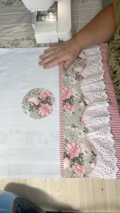 a person is using a sewing machine to sew on a piece of fabric with pink flowers