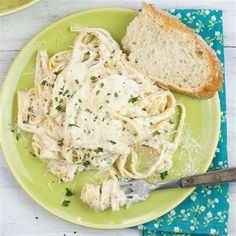 a green plate topped with pasta and bread next to a slice of bread on top of a blue napkin