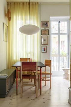 a dining room table and chairs in front of a large window with yellow drapes