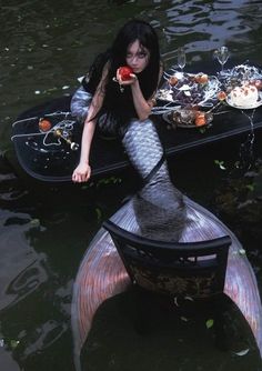 a woman sitting on top of a boat in the middle of water holding an apple