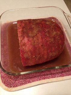 a square glass dish filled with food on top of a pink towel next to a white counter