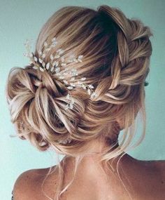 a woman with braids and flowers in her hair is wearing a wedding hairstyle