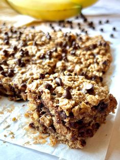 chocolate chip oatmeal breakfast bars on parchment paper with bananas in the background