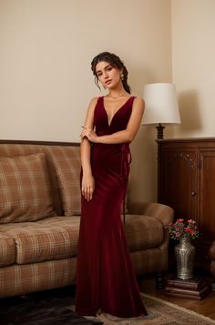 a woman standing in front of a couch wearing a red dress