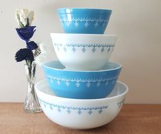 a stack of bowls sitting on top of a wooden table next to a vase with flowers