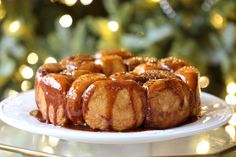 a bundt cake sitting on top of a white plate next to a christmas tree