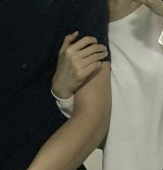 the man is wearing a white shirt and has his arm around another person's shoulder