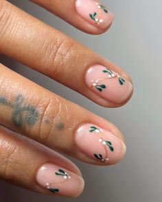 These short nails feature a nude base with dainty mistletoe art in green and white, accented with a touch of gold. The design adds a festive but subtle charm, perfect for the winter season. This look is ideal for anyone wanting understated holiday-inspired nails. Simple Classy Winter Nails, Almond Short Nails Christmas, Short Nail Ideas Winter 2024, Mild Christmas Nails, Short Natural Nails Christmas, Squoval Holiday Nails, Green And Nude Christmas Nails, Red Nails With Holly, Short Nails Ideas Winter Natural