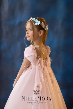 Step into a world of enchantment with our Floral Reverie Luxury Flower Girl Dress, where elegance meets sophistication. This exquisite gown showcases a stunning array of delicate blooms, intricately woven into the soft, flowing fabric, capturing the essence of a lush garden in full bloom. The upper bodice features nude mesh sleeves that gracefully extend to create an ethereal silhouette, allowing for a timeless yet modern touch. Adding a touch of magic, the removable cape wings flow beautifully Natural Pageant, Flower Girl Gown, Floral Embellishment, Pearl Beading, Exquisite Gowns, Kids Gown, Princess Inspired, Blue Gown, Gowns For Girls