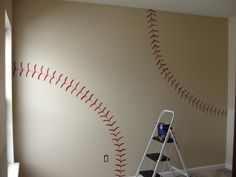 a baseball wall decal with red stitches on it and a ladder leaning against the wall