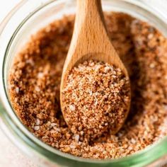 a wooden spoon in a glass jar filled with ground cinnamon and seasoning flakes