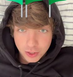 a young man with three green toothbrushes on his head and two white plastic forks sticking out of his hair