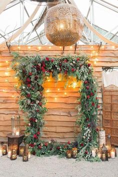 a wooden structure with candles and greenery on it, surrounded by lights in the background