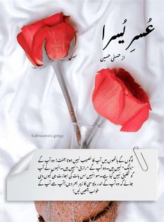 two red roses sitting in a vase on top of a white sheet with arabic writing