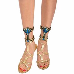 a woman's legs wearing gold sandals with blue flowers on them