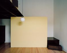 an empty room with wood flooring and a lamp hanging from the ceiling above it