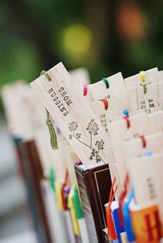 many small books are lined up on a table with markers and ribbons attached to them