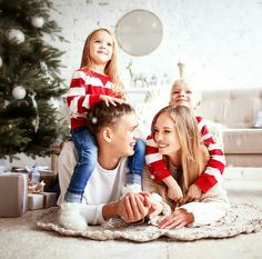 a man and two children sitting on the floor near a christmas tree