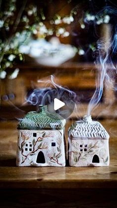 two ceramic houses sitting on top of a wooden table