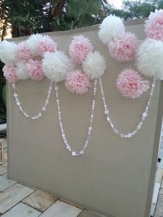 some pink and white pom poms hanging from a wall