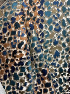 an animal print fabric with blue, brown and green spots on it's surface