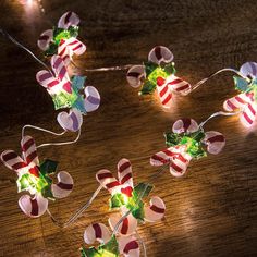 christmas lights with candy canes on them are sitting on a wooden table and lit up