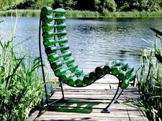 a green chair sitting on top of a wooden dock next to a body of water