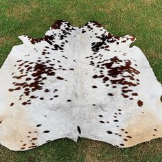 a brown and white spotted cowhide rug on grass