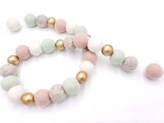 a close up of a necklace on a white surface with gold and pink beads around it